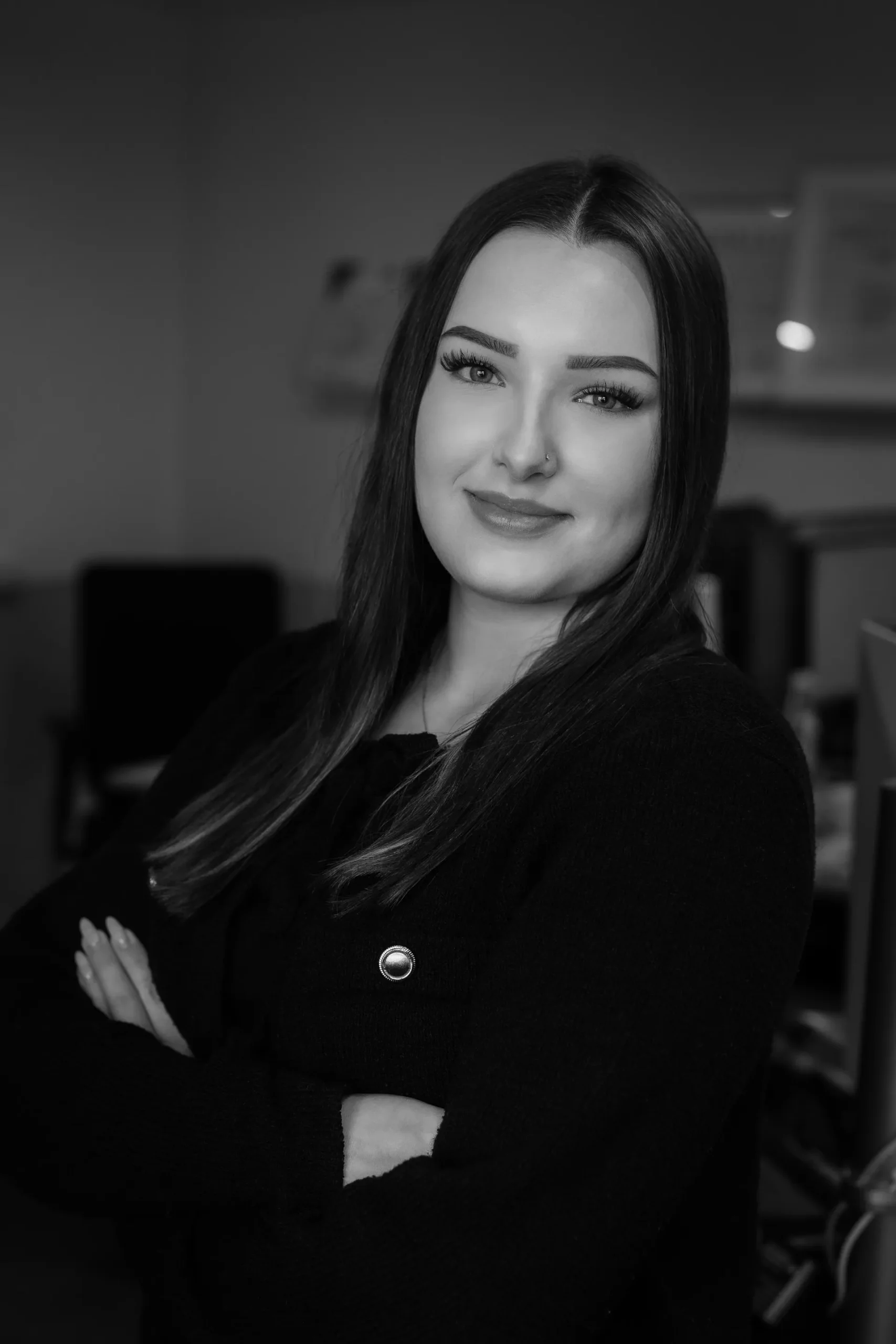 Porträt einer lächelnden Mitarbeiterin mit verschränkten Armen.