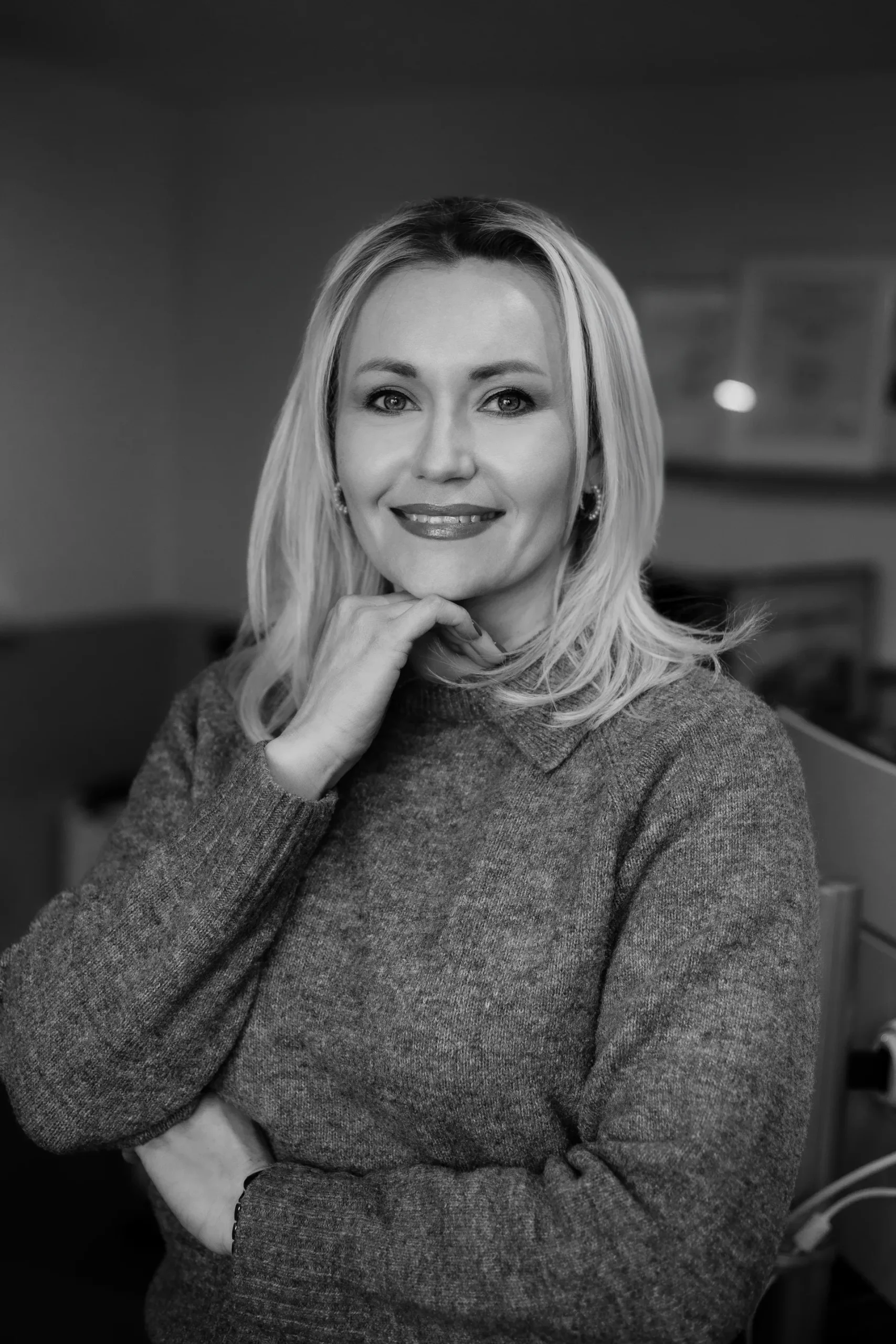 Porträt einer lächelnden Mitarbeiterin im hellen Pullover.