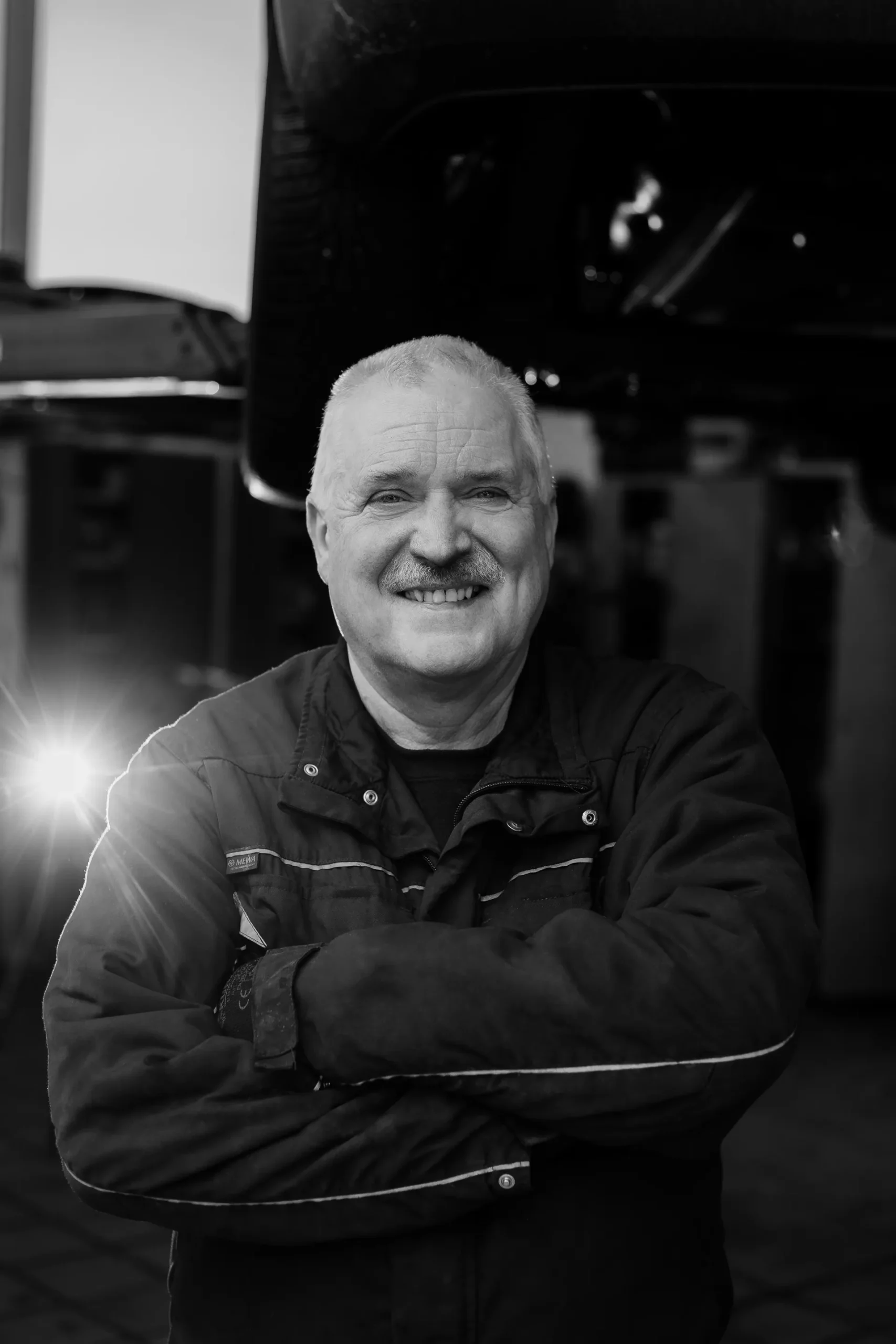 Porträt eines älteren, lächelnden Mitarbeiters in der Werkstatt.